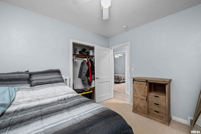 bedroom with a closet, baseboards, ceiling fan, and light carpet