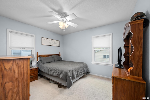 bedroom featuring baseboards, light carpet, a ceiling fan, and a textured ceiling
