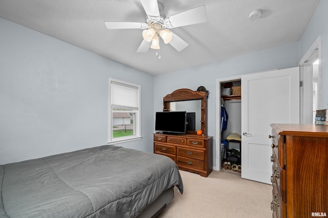 bedroom with ceiling fan, light colored carpet, and a closet