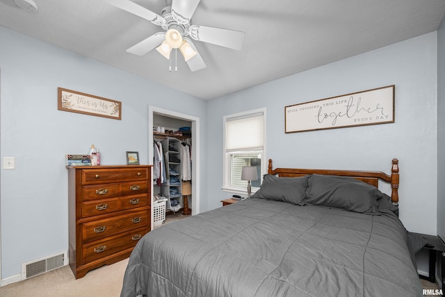 bedroom with ceiling fan, light colored carpet, a walk in closet, visible vents, and a closet