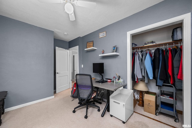 carpeted office space featuring baseboards and a ceiling fan