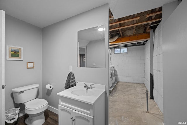 bathroom featuring toilet, concrete flooring, washing machine and dryer, and vanity