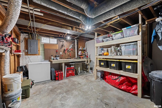 unfinished basement with refrigerator, a workshop area, and electric panel