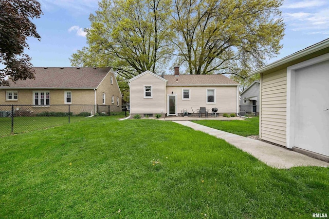 rear view of house with fence, a chimney, a lawn, and a patio area