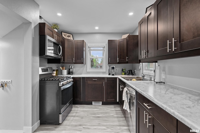 kitchen featuring light countertops, light wood-style flooring, appliances with stainless steel finishes, and dark brown cabinetry