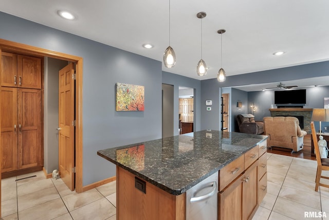 kitchen featuring a kitchen island, ceiling fan, brown cabinets, light tile patterned floors, and decorative light fixtures