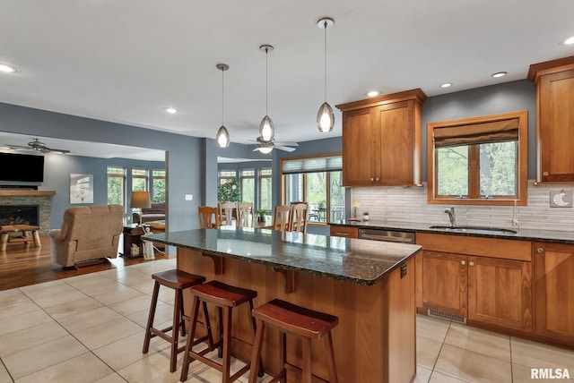 kitchen with light tile patterned floors, ceiling fan, open floor plan, and a sink