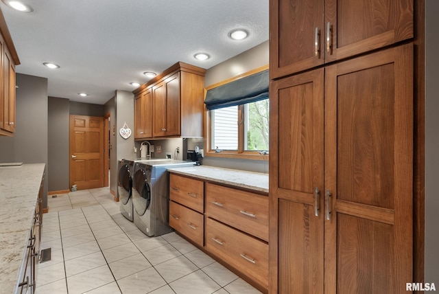 clothes washing area featuring baseboards, recessed lighting, washing machine and clothes dryer, cabinet space, and light tile patterned floors