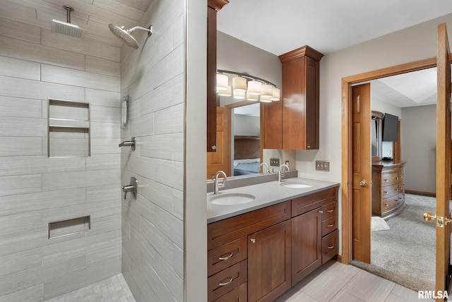 ensuite bathroom with double vanity, a sink, connected bathroom, and a tile shower