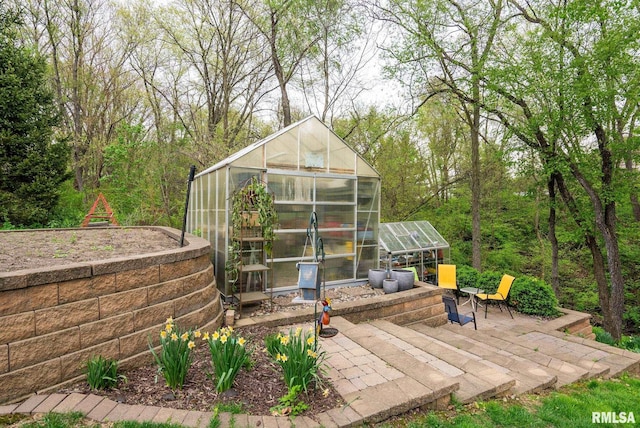 wooden terrace featuring a patio, a greenhouse, and an outdoor structure