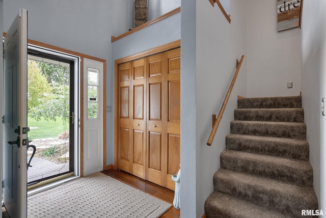 entryway featuring stairway, wood finished floors, and a towering ceiling