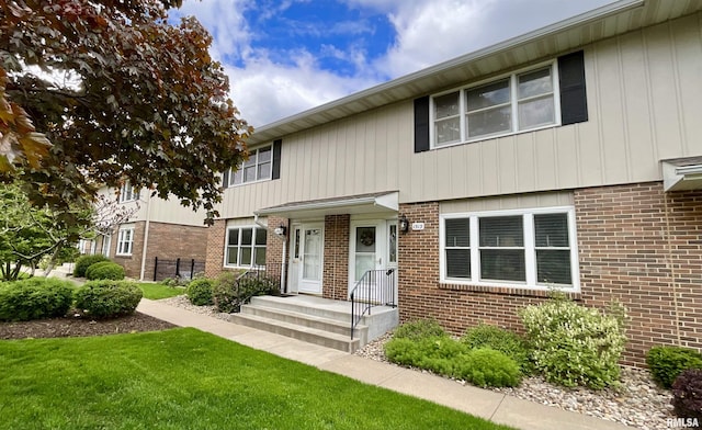 view of front of home featuring fence, a front yard, and brick siding
