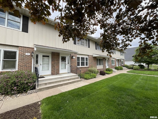 townhome / multi-family property with a front lawn and brick siding