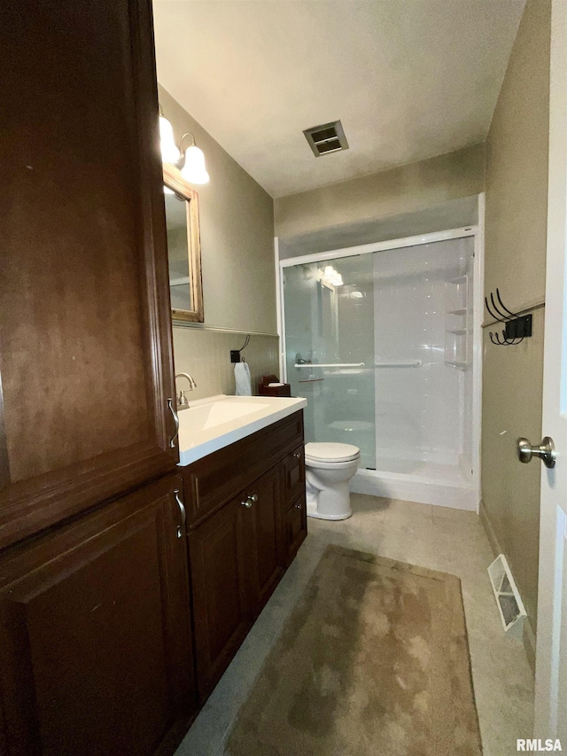 bathroom with vanity, a shower stall, toilet, and visible vents