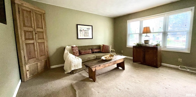 living area with baseboards, visible vents, and light carpet