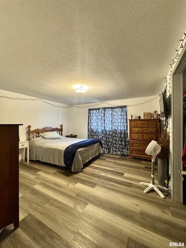 bedroom with a textured ceiling and wood finished floors