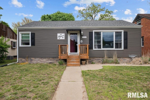 view of front of property featuring central AC unit, roof with shingles, and a front lawn