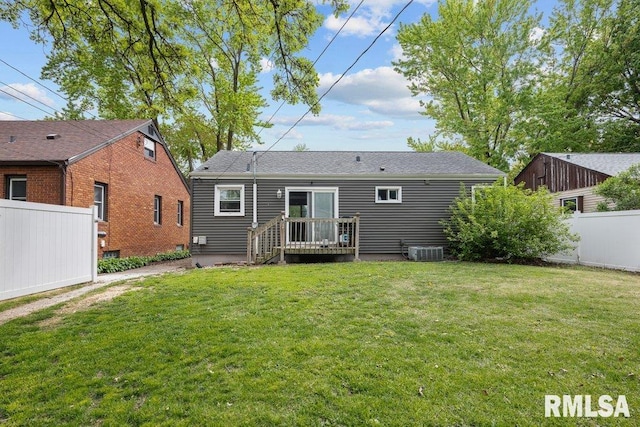 rear view of house featuring central AC unit, fence, and a lawn