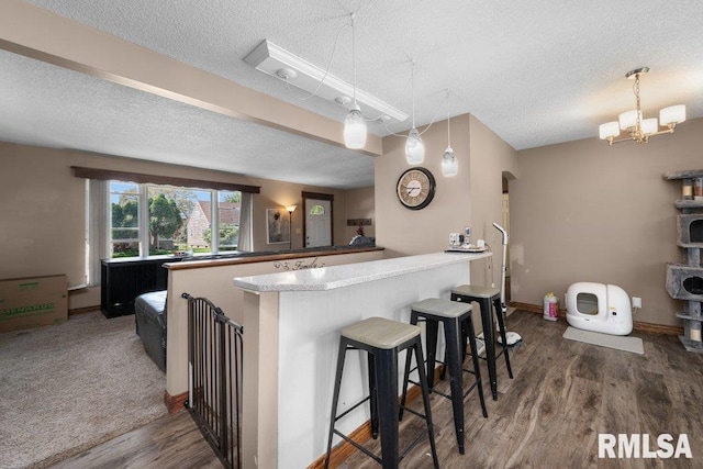 kitchen with a breakfast bar, decorative light fixtures, a textured ceiling, and wood finished floors