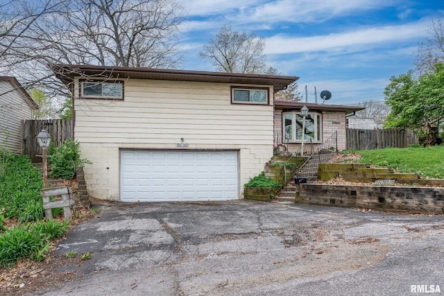 view of front of house featuring aphalt driveway, fence, and an attached garage