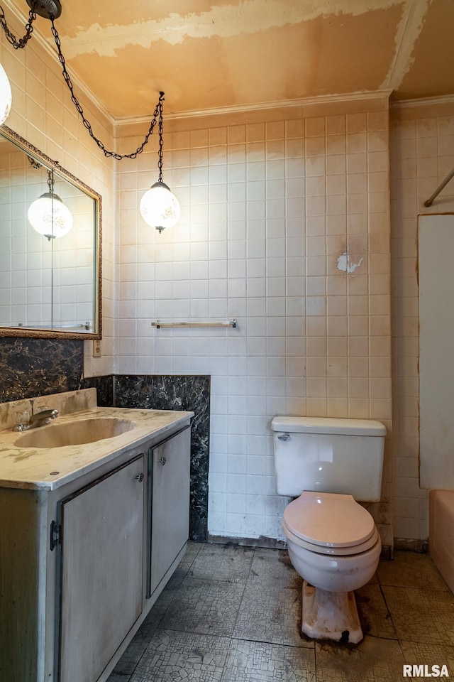 bathroom with toilet, tile walls, ornamental molding, and vanity