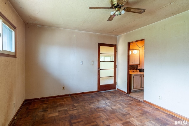 unfurnished room featuring a ceiling fan and baseboards