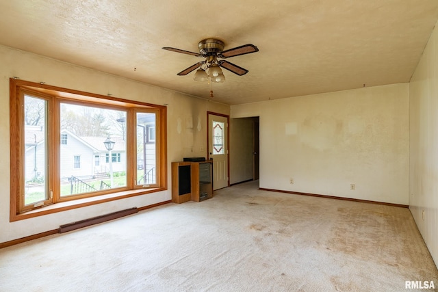 unfurnished living room with a wealth of natural light, baseboards, a baseboard heating unit, and carpet floors