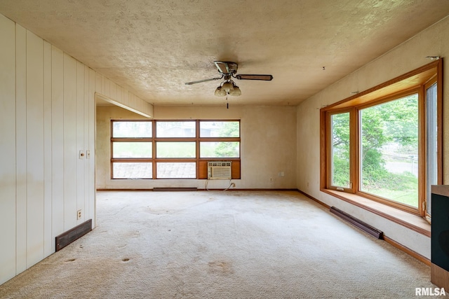 unfurnished room with a textured ceiling, carpet, ceiling fan, a wall unit AC, and baseboard heating
