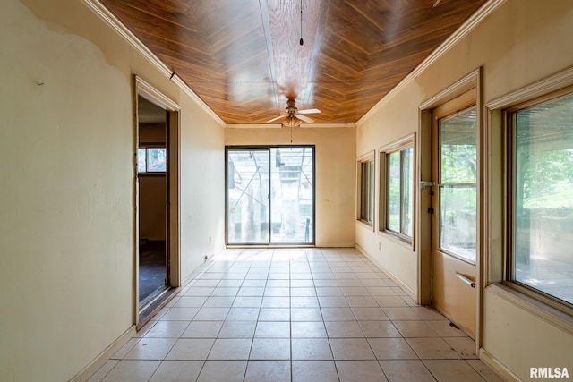 empty room featuring a ceiling fan, crown molding, light tile patterned flooring, and wood ceiling