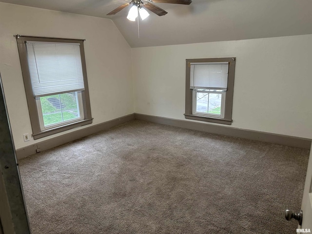 carpeted empty room with a ceiling fan, baseboards, lofted ceiling, and a healthy amount of sunlight
