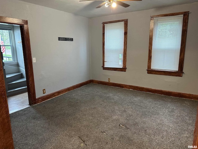 spare room featuring dark colored carpet, baseboards, and a ceiling fan
