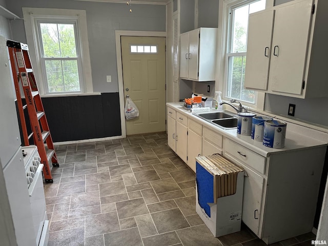 kitchen featuring light countertops, stone finish flooring, a healthy amount of sunlight, and a sink
