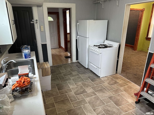 kitchen with white appliances, light countertops, white cabinets, and a sink