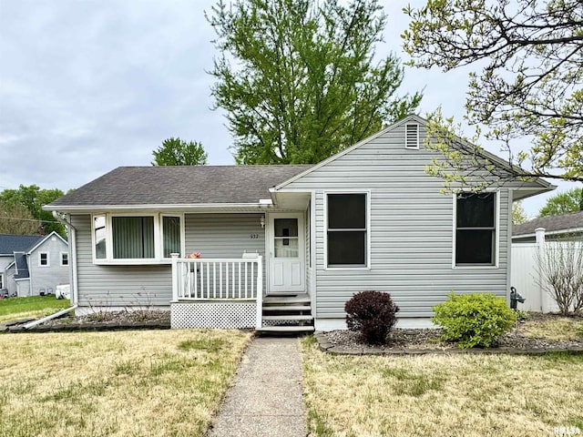 view of front of house with fence, a shingled roof, and a front yard