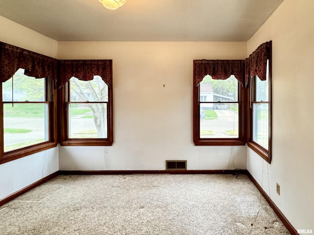 empty room with a healthy amount of sunlight, carpet, and visible vents