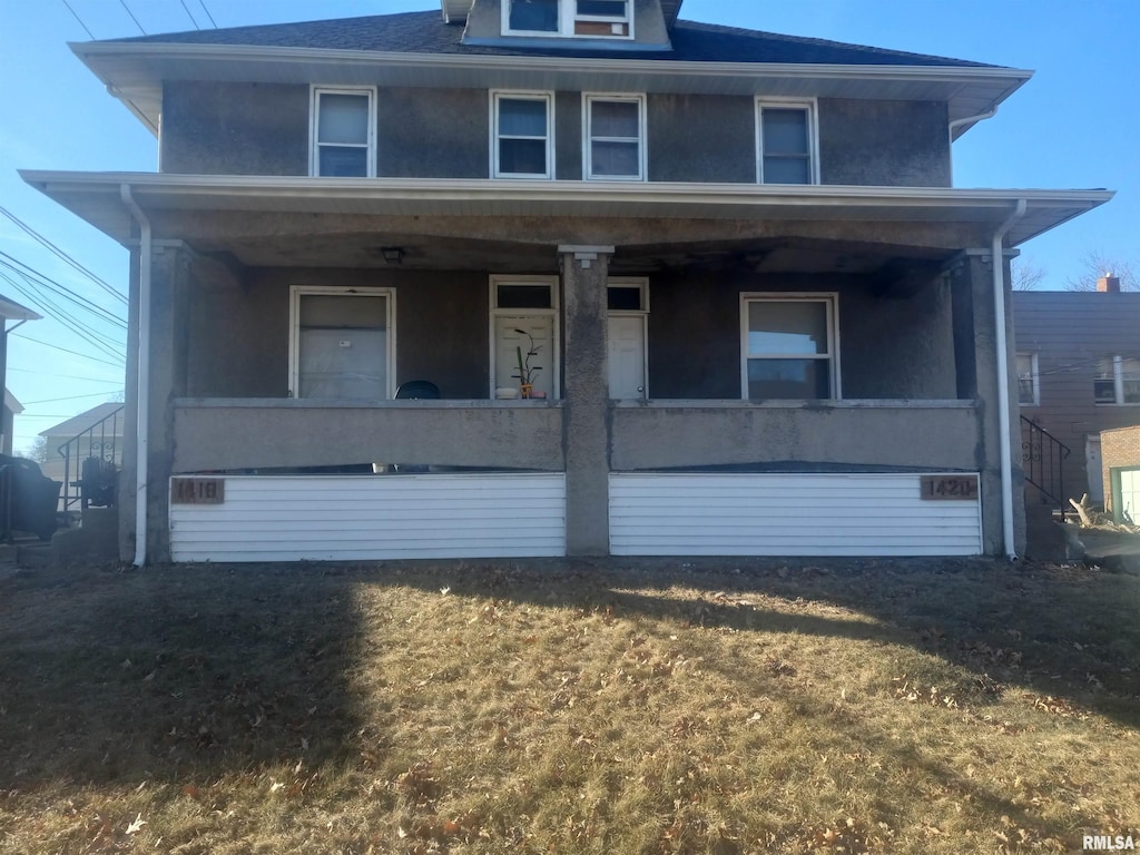 american foursquare style home featuring stucco siding and a porch