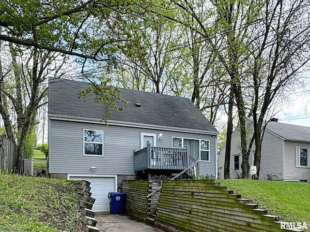 rear view of house featuring roof with shingles, stairs, a garage, and fence