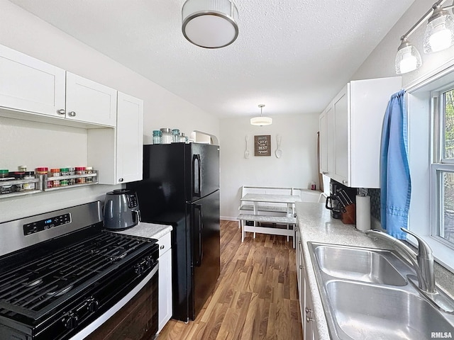 kitchen with stainless steel range with gas cooktop, a sink, light countertops, and wood finished floors
