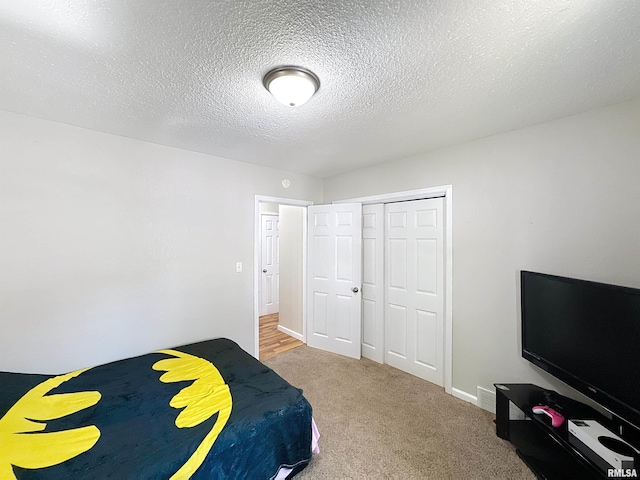 carpeted bedroom featuring a textured ceiling, a closet, and baseboards