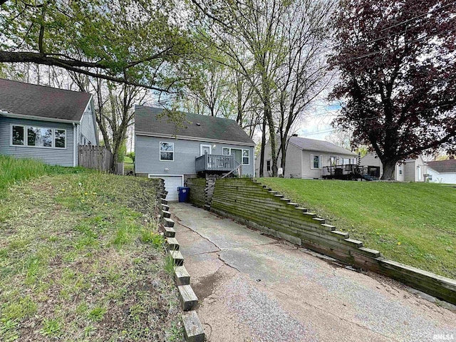 exterior space with driveway, a deck, fence, and an attached garage