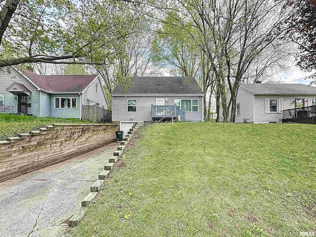 exterior space with an attached garage, a wooden deck, driveway, and a lawn