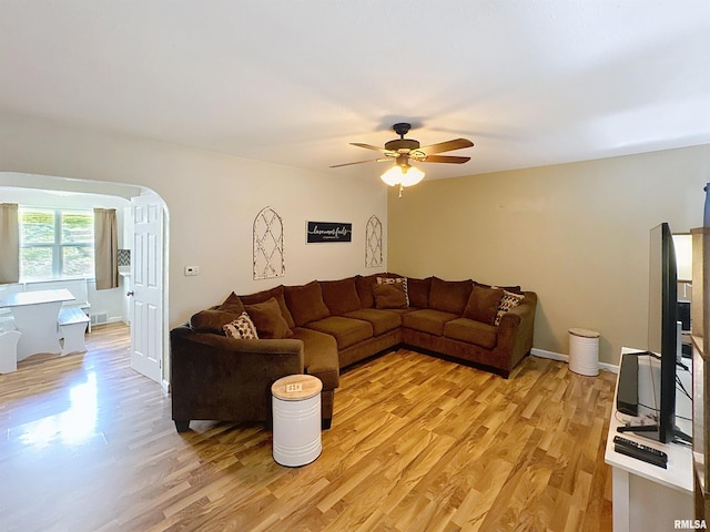 living area with arched walkways, a ceiling fan, visible vents, and light wood-style floors