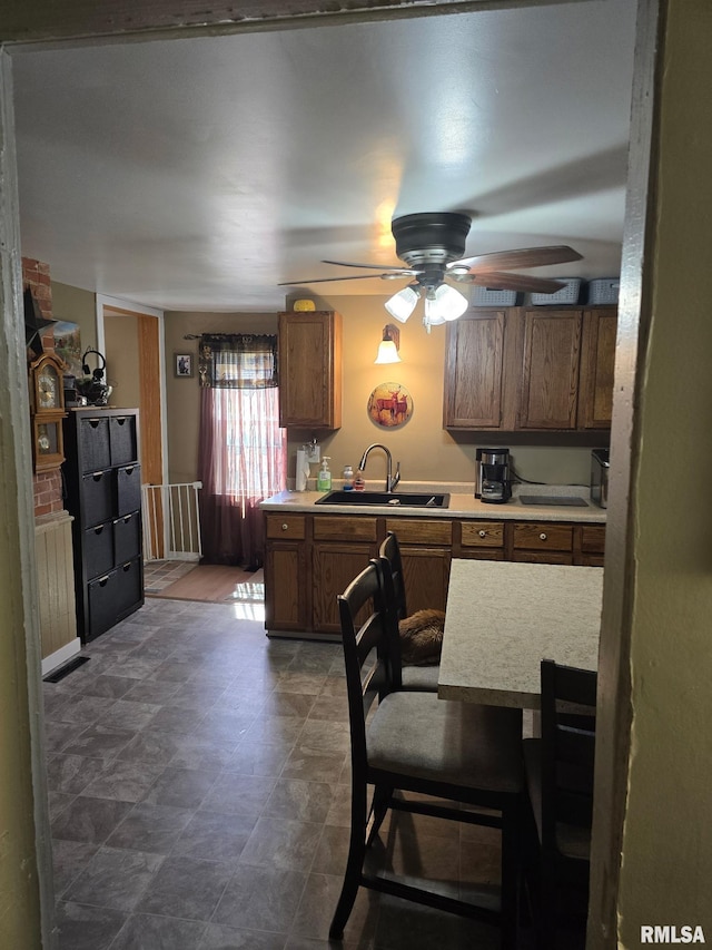 717 NE 2nd St, Galva, IL 61434 - kitchen featuring a sink, ceiling fan, light countertops, and brown cabinets
