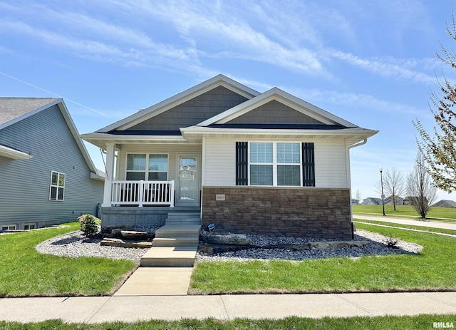 view of front facade with covered porch, a front lawn, and stone siding