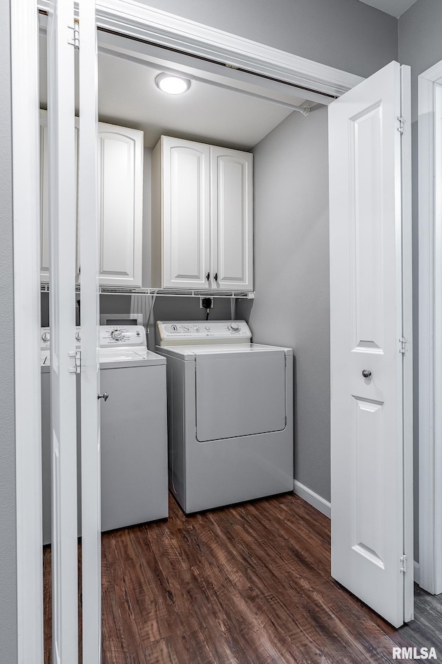 clothes washing area with washing machine and clothes dryer, baseboards, cabinet space, and dark wood-type flooring