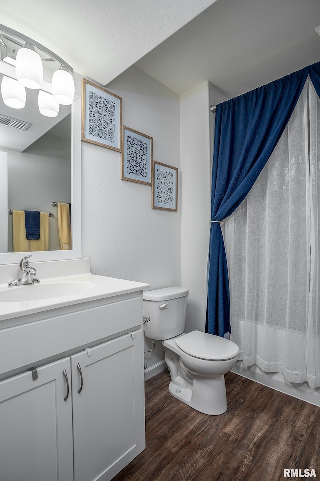 bathroom with toilet, wood finished floors, vanity, visible vents, and shower / bath combination with curtain