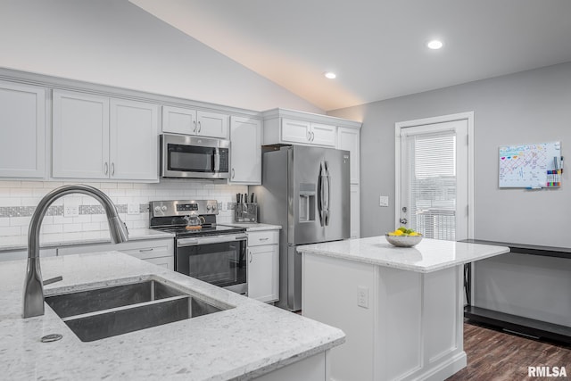 kitchen with a center island, light stone counters, a sink, backsplash, and appliances with stainless steel finishes