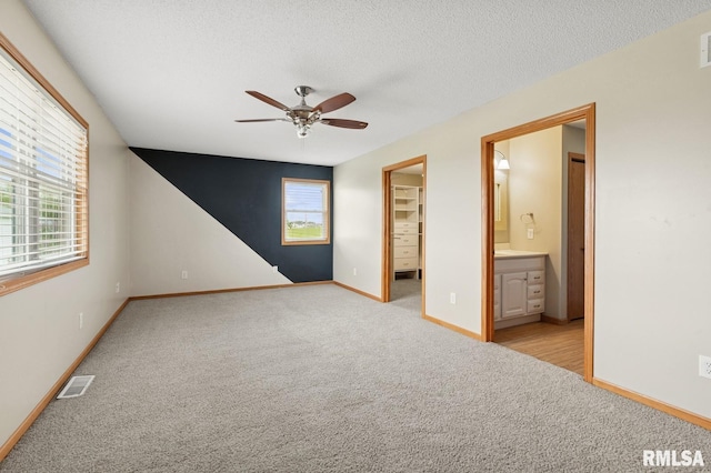 unfurnished bedroom with light colored carpet, a spacious closet, and multiple windows