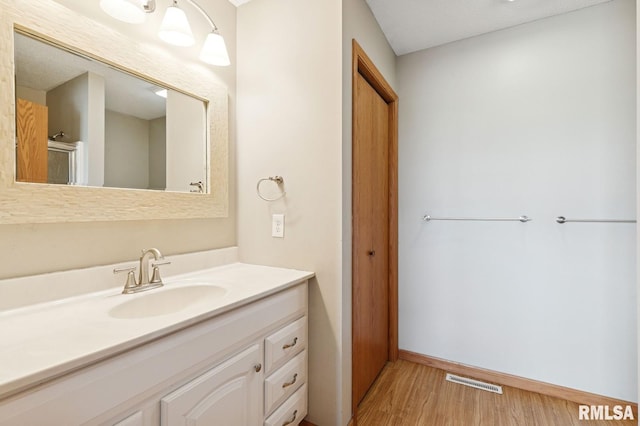 bathroom featuring baseboards, visible vents, wood finished floors, and vanity
