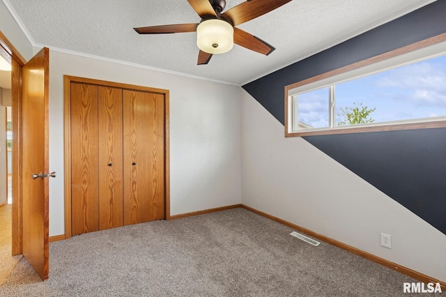 unfurnished bedroom featuring carpet floors, a textured ceiling, a closet, and visible vents